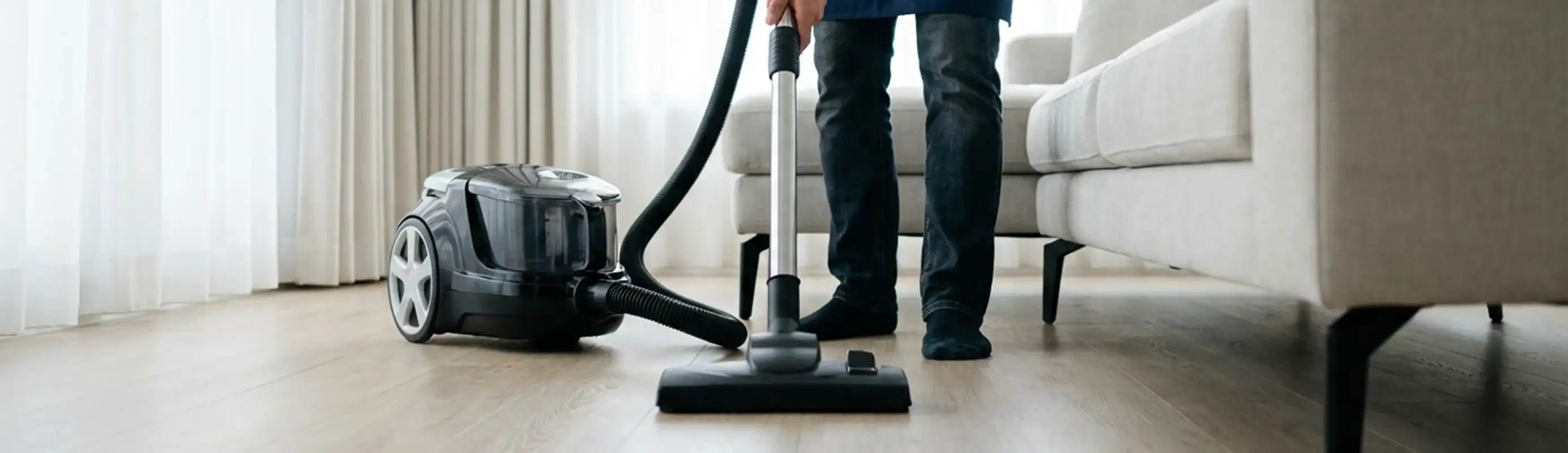 Professional house cleaner vacuuming a living room floor with a canister vacuum cleaner, Naperville, IL.