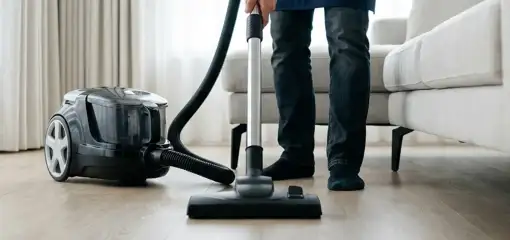 Professional house cleaner vacuuming a living room floor with a canister vacuum cleaner, Naperville, IL.
