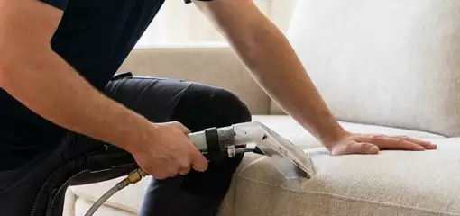 Professional upholstery cleaner deep-cleaning a fabric sofa with a handheld extraction tool, Naperville, IL.
